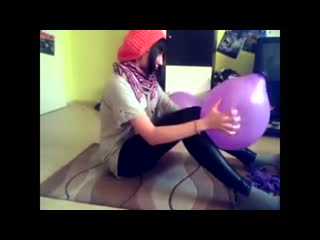 girl blows up several purple balloons and pops them in a variety of manners